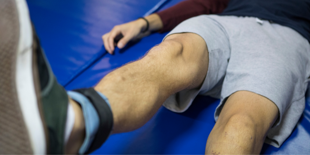 Man in a gym doing a knee excercise.